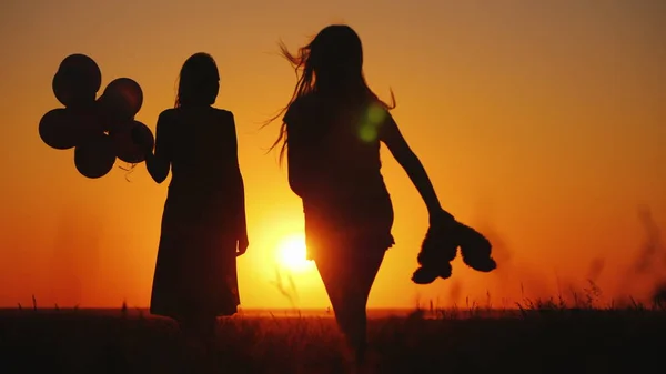 Sorgenfreies Kind mit Spielzeug in der Hand rennt bei Sonnenuntergang zu Mama — Stockfoto