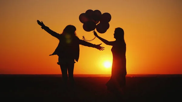 妈妈和女儿在日落时玩得很开心，跳舞和拿着气球 — 图库照片