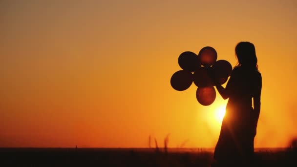 Silhouette of a woman with balloons at sunset. Nostalgia concept — Stock Video
