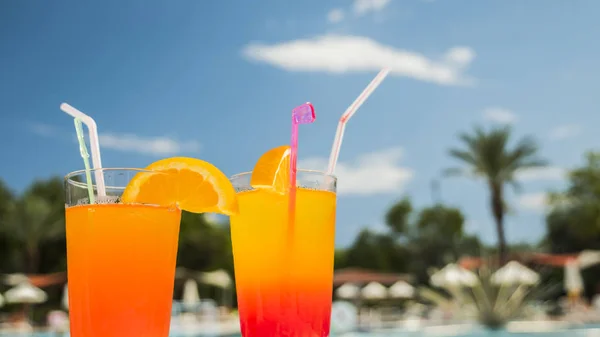 Two glasses with orange cocktail by the pool