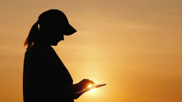 Silhouet van een vrouw boer werken met een Tablet bij zonsondergang — Stockvideo