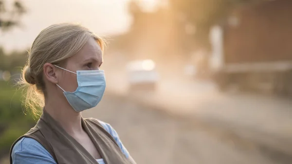 Kobieta w masce ochronnej na zakurzonej drodze. Koncepcja problemów ekologicznych — Zdjęcie stockowe