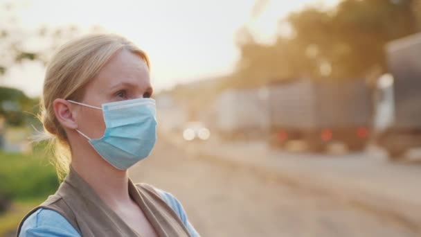Жінка в захисній масці на пиловій дорозі. концепція екологічних проблем — стокове відео