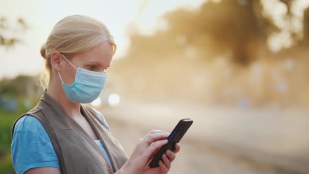 Eine Frau mit Maske zum Schutz vor schmutziger Luft benutzt ein Smartphone. Ökologische Probleme — Stockvideo