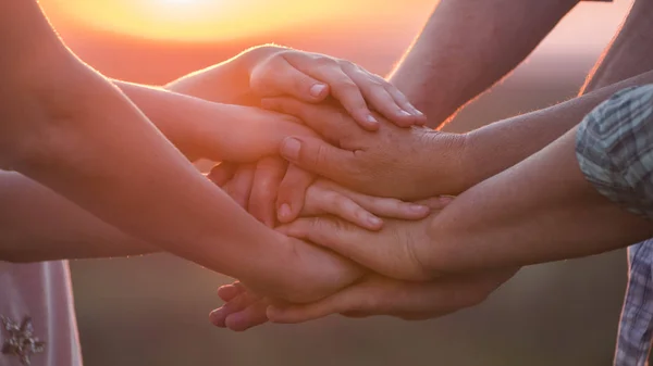 Farklı yaşlardaki bir grup insan ellerini birbirine koyar. Takım çalışması konsepti