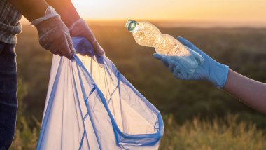 Gönüllüler çöpleri plastik torbalara koyarlar. Parkın temizlenmesi ve çevreyle ilgilenilmesi.