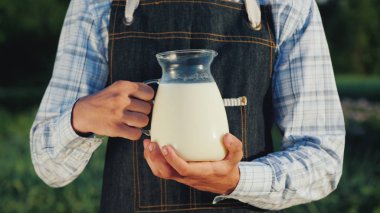 Çiftçi sütlü bir sürahi tutuyor. Organik ürünler konsepti