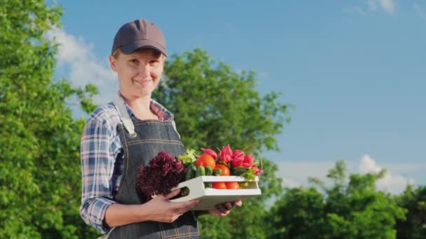 Portret van een vrouwelijke boer met een doos verse groenten uit haar tuin — Stockvideo