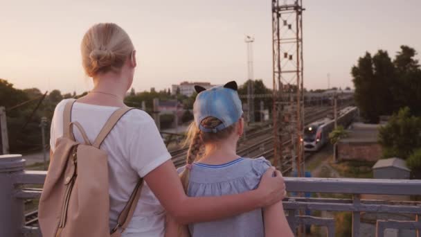 Žena a její dcera stojí na mostech a podívejte se na vlak pod