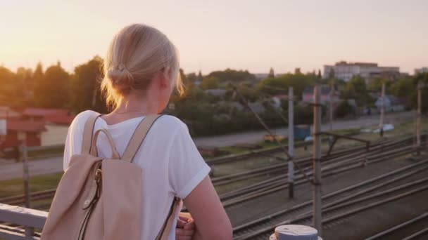 Eenzame vrouw staat op de reling van de brug, kijkt naar de spoorlijn — Stockvideo