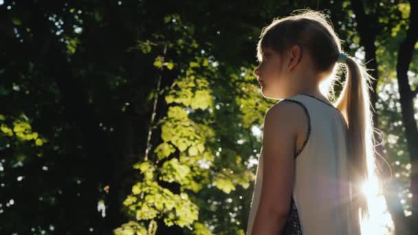 La niña está parada en la viga, el sol brilla en su cara. Piérdete en un bosque de hadas — Vídeo de stock