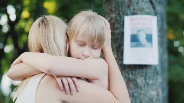 Женщина обнимает ребенка на фоне пропавшей рекламы — стоковое видео
