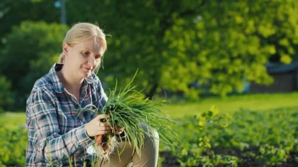 Porträtt av en kvinnlig bonde med en grön lök i händerna. Ekologiskt jordbruk koncept — Stockvideo