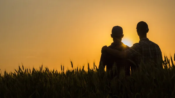 Twee jonge mannen knuffelen tegen de achtergrond van de zonsondergang, kijken uit naar de horizon — Stockfoto