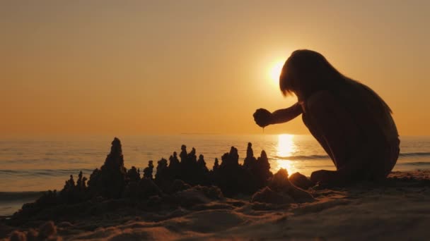 En flicka leker i sanden vid havet, bygger ett vackert slott av våt sand — Stockvideo
