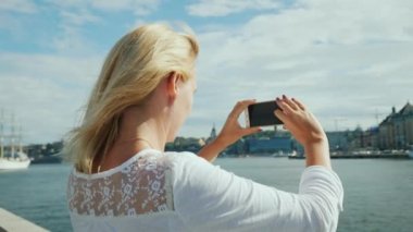 Genç bir kadın Stockholm şehrinin güzel bir manzarasını fotoğraflar. İsveç'te seyahat