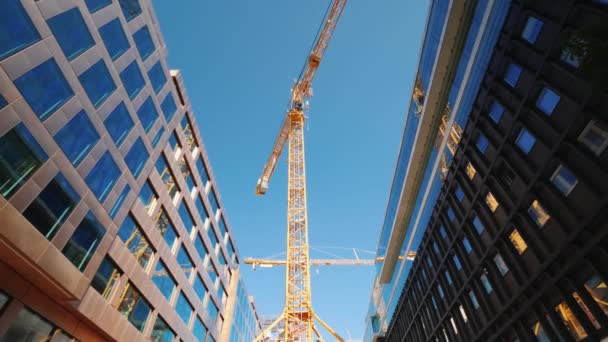 Una grúa torre grande en el centro de la ciudad moderna. Edificios de oficinas de vidrio alrededor. Ancho de ángulo bajo tiro — Vídeos de Stock