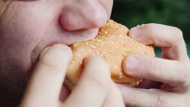 Mund eines erwachsenen Mannes, der gierig einen Hamburger isst