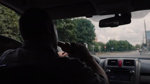 Вид сзади водителя, пьющего алкоголь за рулем. Концепция опасного незаконного поведения — стоковое видео