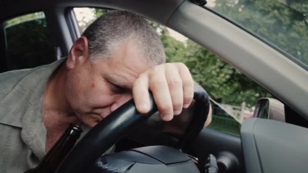 Conductor borracho con una botella de alcohol en la mano durmiendo en el volante — Vídeos de Stock