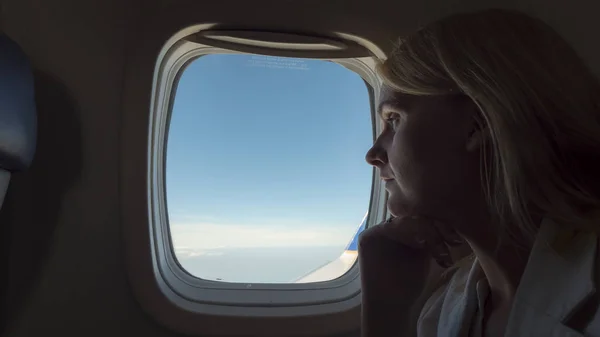 Pensive vrouw kijkt uit het raam van een vliegtuig — Stockfoto