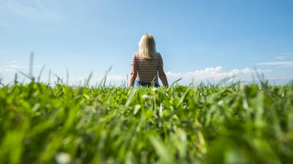 Jonge onherkenbaar vrouw zittend op een groen gazon — Stockfoto