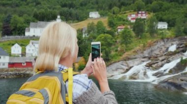 Gezgin Norveç'te pitoresk bir manzara, bir şelale ve geleneksel Norveç evleri fotoğrafları