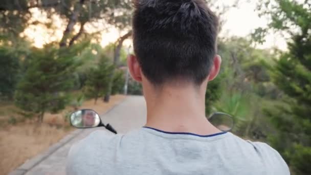 Vista trasera de un adolescente montando una scooter — Vídeo de stock