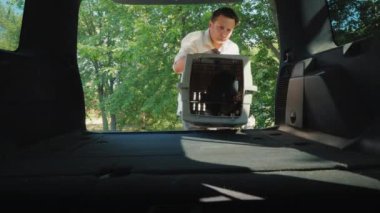 Bir adam bir arabanın bagajında yavru iki kafes koyar. Araçlarda Evcil hayvan taşımacılığı