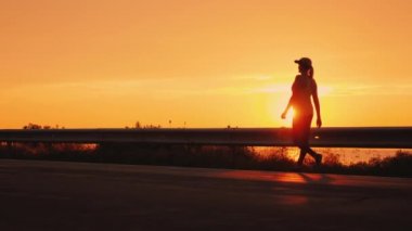 Topuk ve ayak güzel bir yerde yürümek. Bir kadının silueti güneş karşı yol boyunca yürüyüş