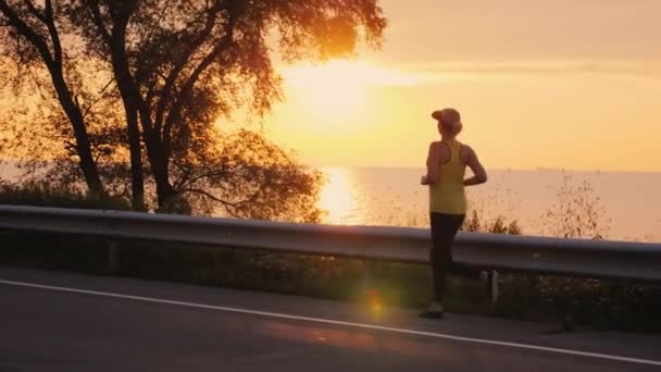 Orta yaşlı kadın günbatımı göl tarafından jogging — Stok video