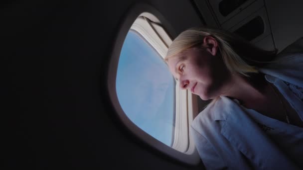 Low angle viev of woman flying in an airplane, looking out the window — Stock Video