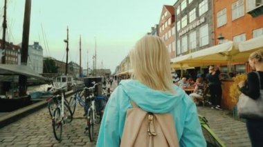 Kopenhag, Danimarka, Temmuz 2018: bir kadın Nyhavn kanal boyunca yürüyüş, ünlü renkli evlerin arka plana karşı. Turistler arasında en popüler yer Kopenhag, Danimarka olduğunu