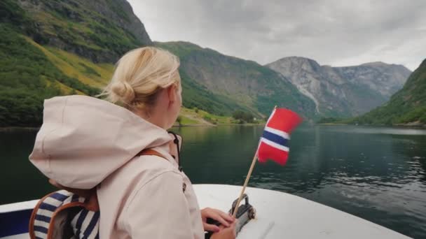 Mujer activa con la bandera de Noruega en la proa del barco. Cruceros en fiordo, viaje a Escandinavia — Vídeos de Stock