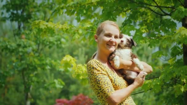 Glückliche Frau mittleren Alters kuschelt nassen Welpen. Sie stehen im Garten im Regen. Unvergessliche Momente des Lebens — Stockvideo