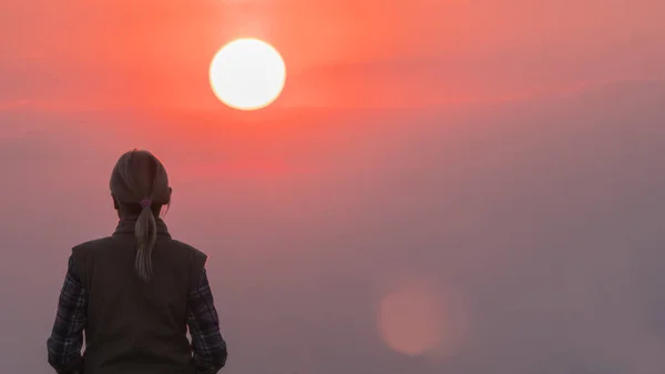 女人对粉红色天空和红太阳大盘的孤独力量 — 图库照片