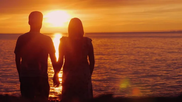 Romantická multietnická dvojice obdivuje malebný západ slunce nad mořem. Držím ruce, zadní pohled. Harmonie v koncepci vztahu — Stock fotografie