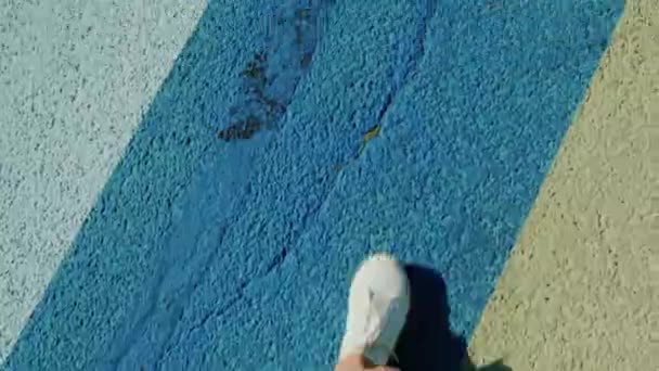 Visão em primeira pessoa de pés andando em sapatos esportivos andando no asfalto colorido variegado — Vídeo de Stock