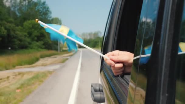 Ruka se švédským praporkem v autě. Cestování po Skandinávii — Stock video
