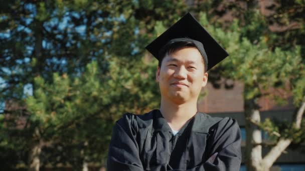 Asiatischer junger Mann in Diplomkleidung. Hochschulabschlusskonzept — Stockvideo