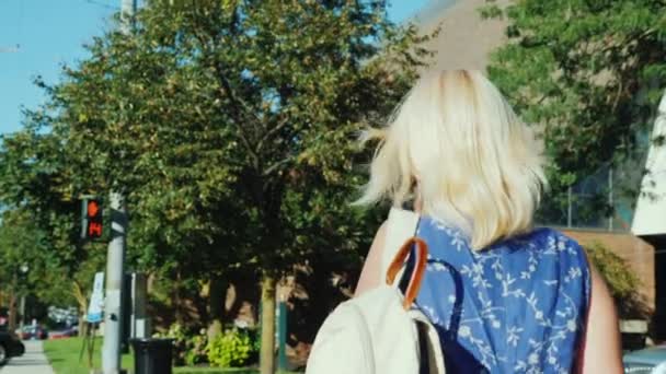 Μια ξανθιά γυναίκα με σακίδιο διασχίζει το δρόμο. Αντίστροφη μέτρηση στο φανάρι. Γρήγορος ρυθμός ζωής — Αρχείο Βίντεο