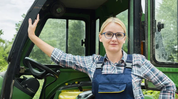 Porträtt av en bonde kvinna. Stående nära sin traktor, titta på kameran — Stockfoto