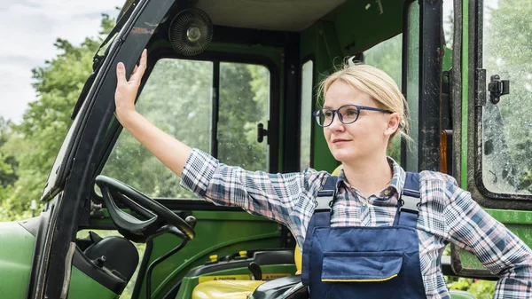 Porträtt av en bonde kvinna. Stående nära sin traktor — Stockfoto