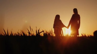 Anne ve kızı günbatımı, el ele tutuşarak hayran. Mutlu çocukluk kavramı