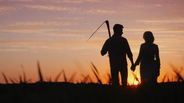 Pareja joven de agricultores en el campo, disfrutando de la puesta de sol. Inicio en el concepto de agroindustria — Vídeos de Stock