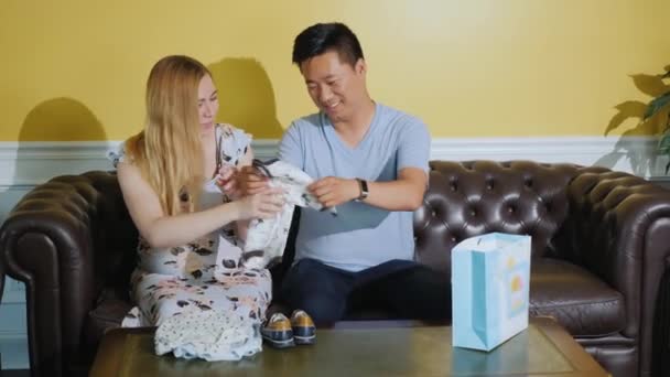 Jeune couple multi-ethnique regardant des achats pour leur bébé à naître — Video