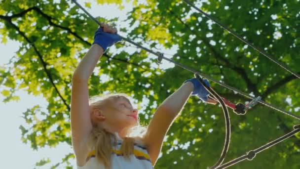 Actief kind klimt onverschrokken de touwen tussen de bomen — Stockvideo