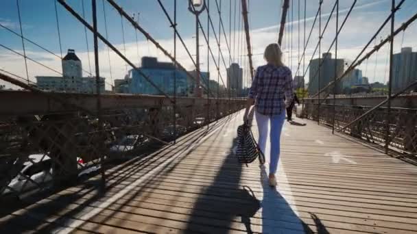 Elinde sırt çantası olan kaygısız kadın sabahın erken saatlerinde Brooklyn Köprüsü'ne çıkıyor. New York'ta Sabah — Stok video