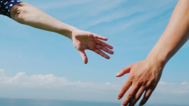 Az ifjú pár kezet tart egy kék égbolton — Stock videók
