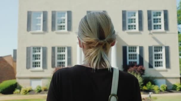 Resmi kıyafetli bir kadın binaya doğru yürüyor, arka görüşe. Bir ofis binasına veya kiliseye giriş — Stok video